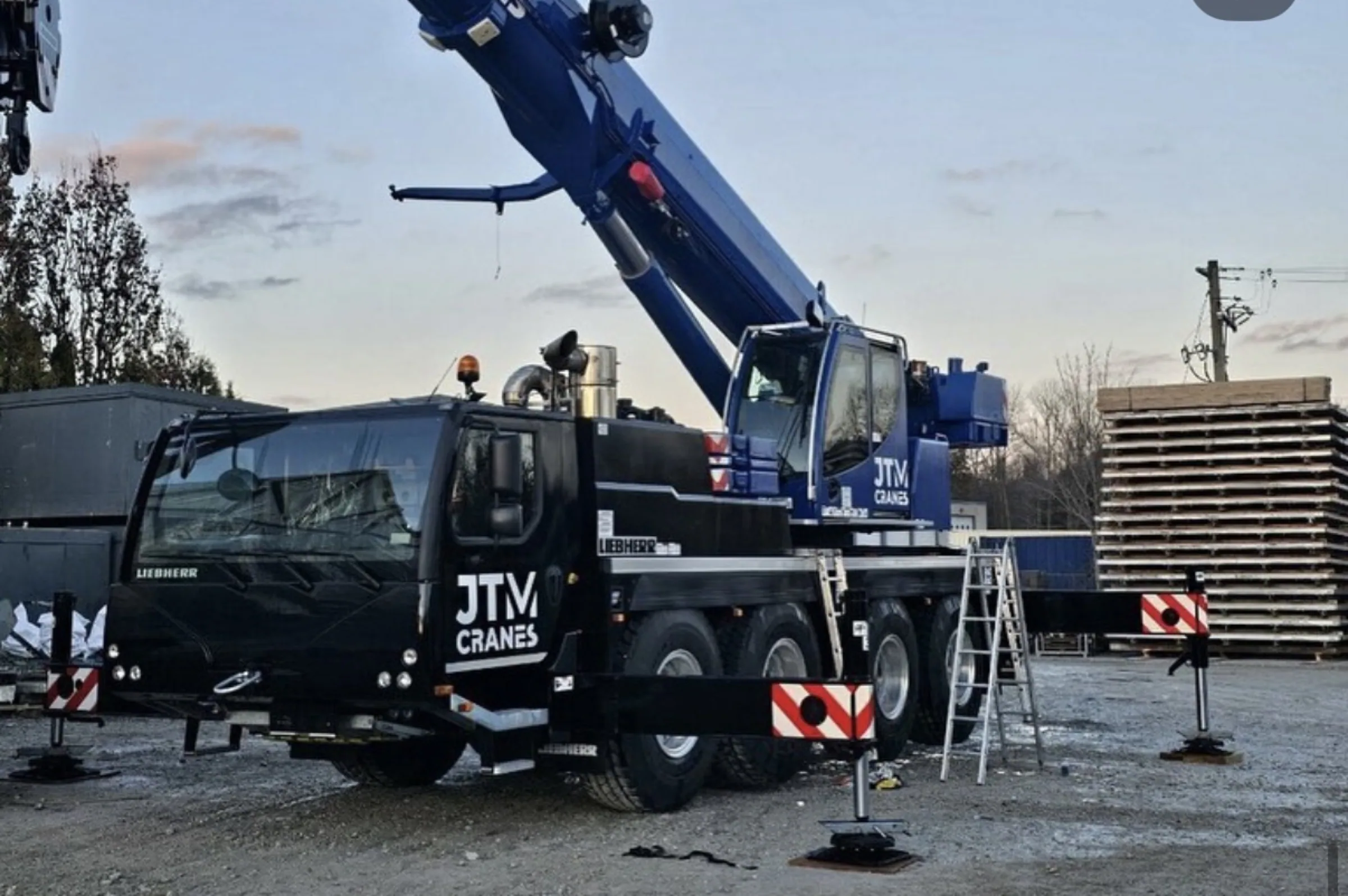 JTM Cranes machine set up on mats at a jobsite in the evening
