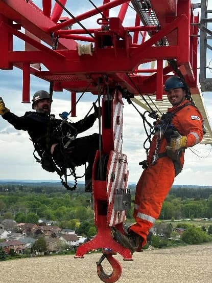 Two riggers working at height on a tower crane during an erection