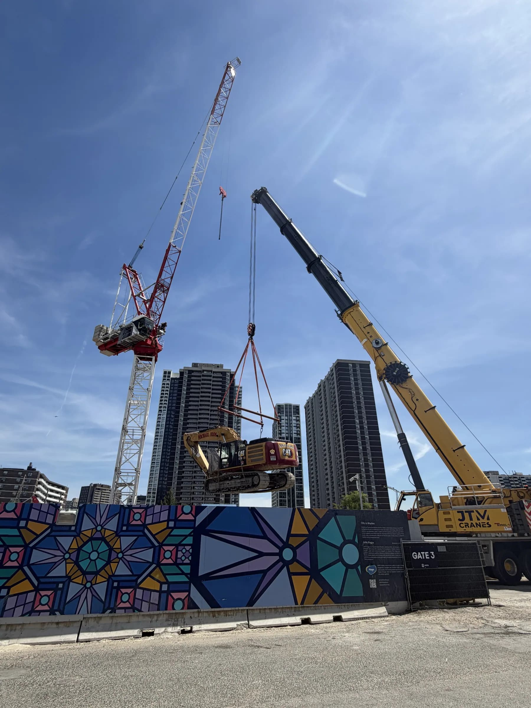 Two tower cranes and a JTM Cranes mobile crane on a downtown construction site